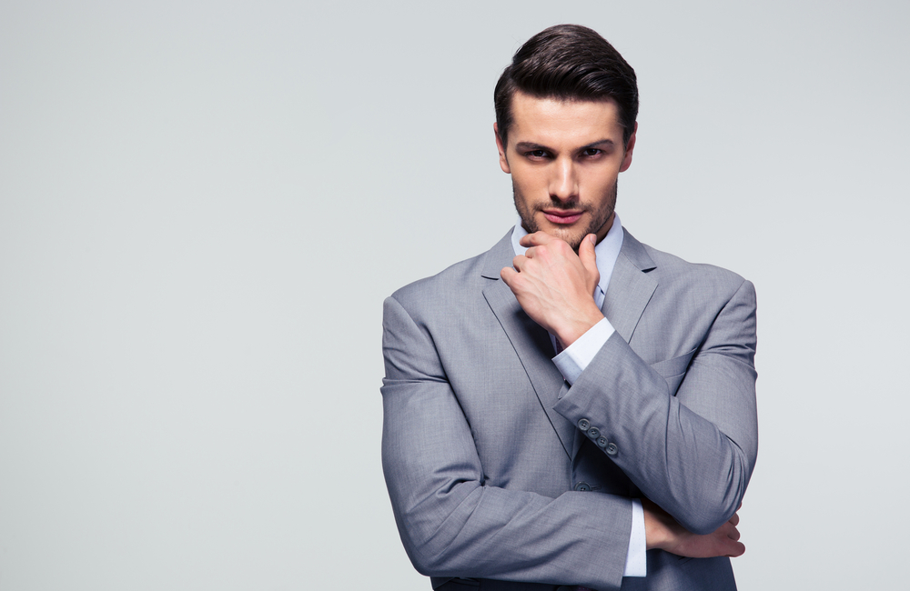 Portrait of a pensive businessman touching his chin over gray background Portrait of a pensive businessman touching his chin over gray background